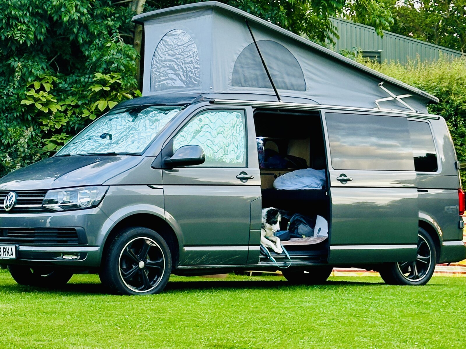 Daisy the VW T6 campervan with her pop-top roof raised, pitched on grass