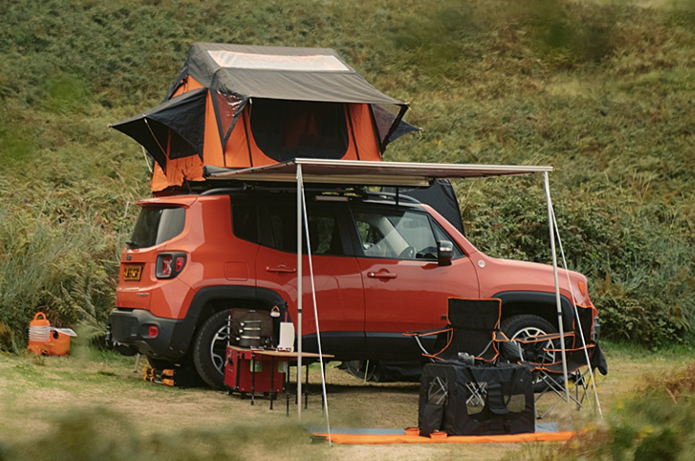 Jack, the Jeep Renegade Trailhawk, pitched on grass with the rooftop tent open and the side awning extended