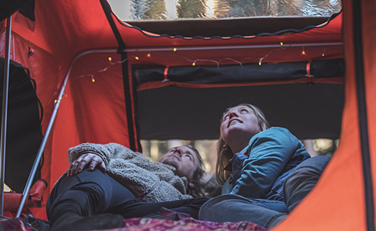 Inside the rooftop tent at night with fairy lights strung across the roof